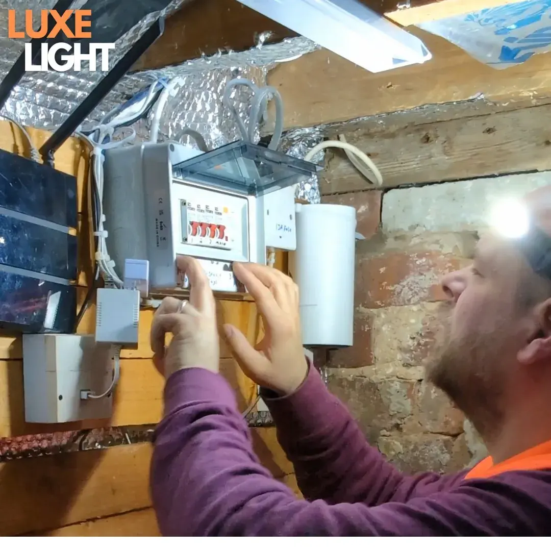 Électricien qui travaille sur un tableau, éclairé par la lampe